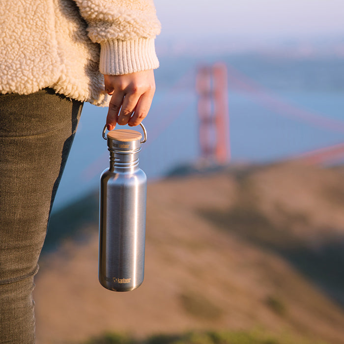 27oz-reflect-with-bamboo-cap-r0 K27SSLRF-BS-BAMBOO_reflect_bottle_bridge_lifestyle.jpg